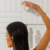 Woman spraying hair product in hair