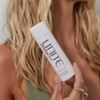 Model holding bottle close to hair