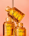 three gold bottles of hair oil stacked together