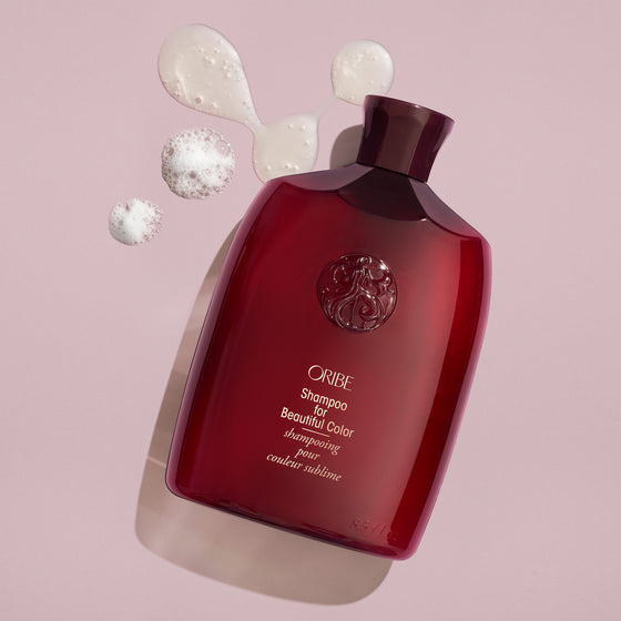 Red bottle of Oribe shampoo on pink background